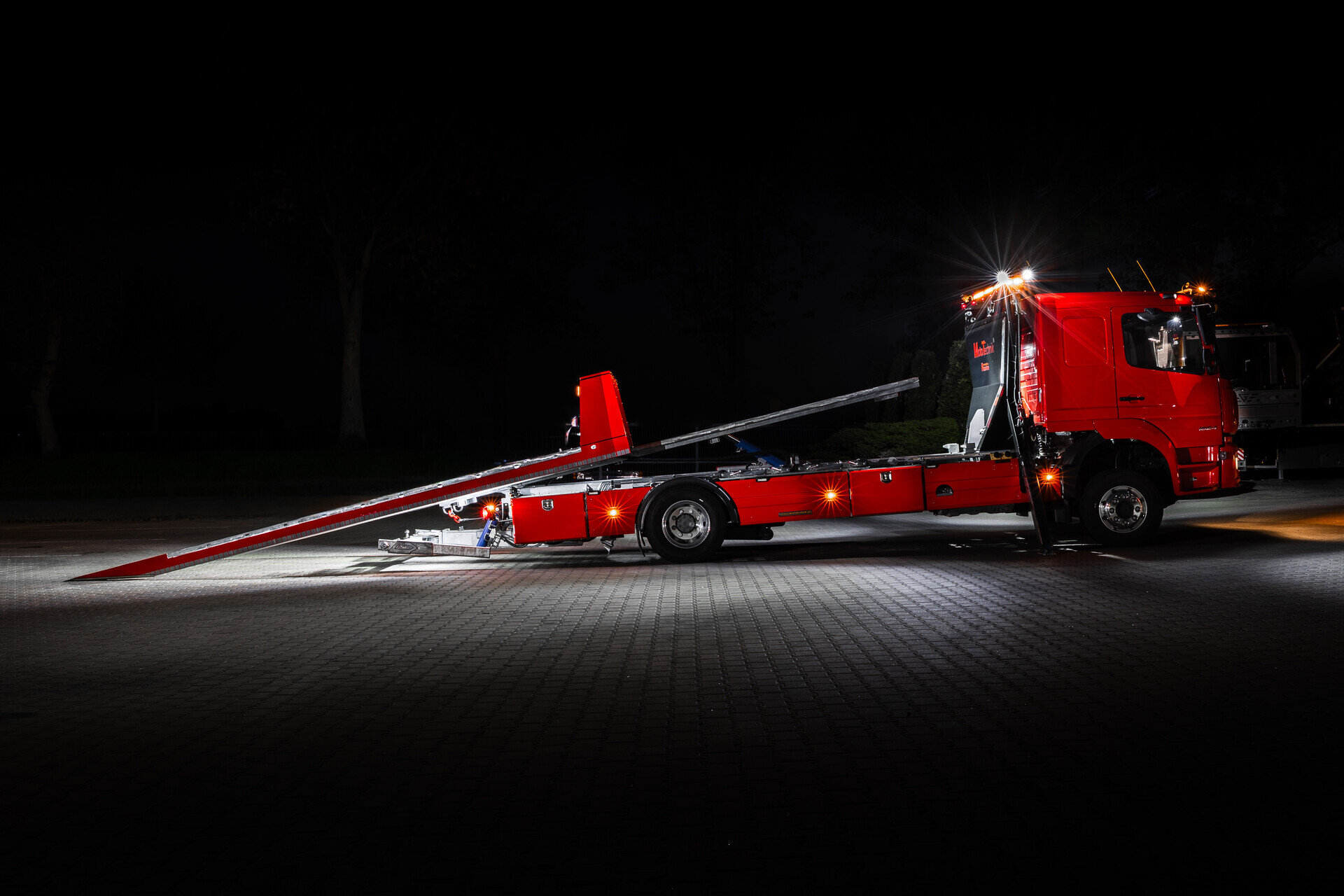 Czerwony samochód z hydrauliczną platformą do transportu pojazdów