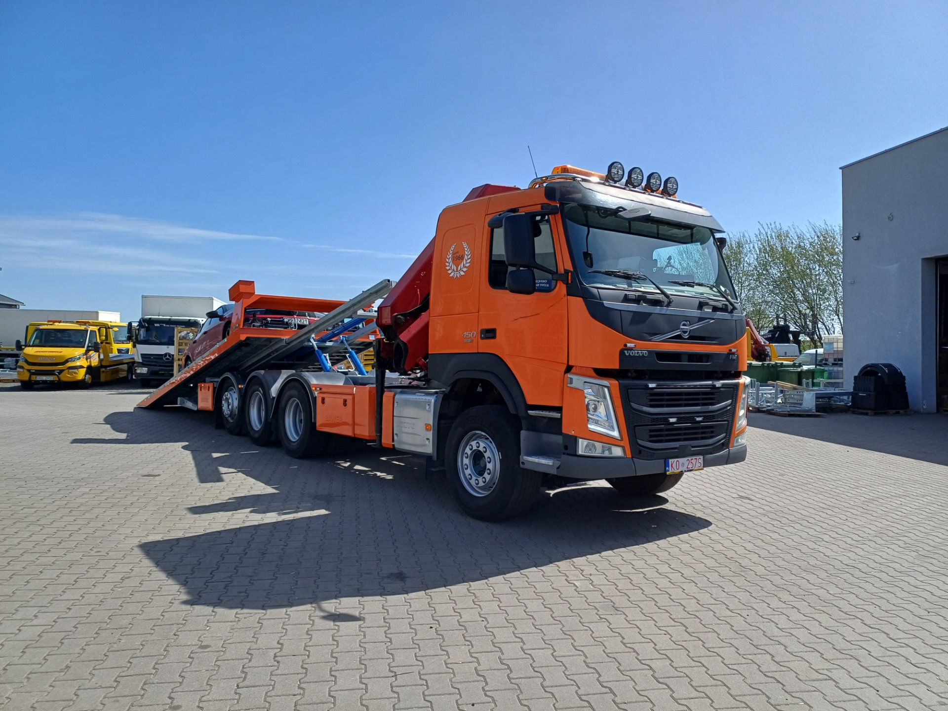 Pomarańczowy samochód Volvo FM 450 z platformą hydrauliczną