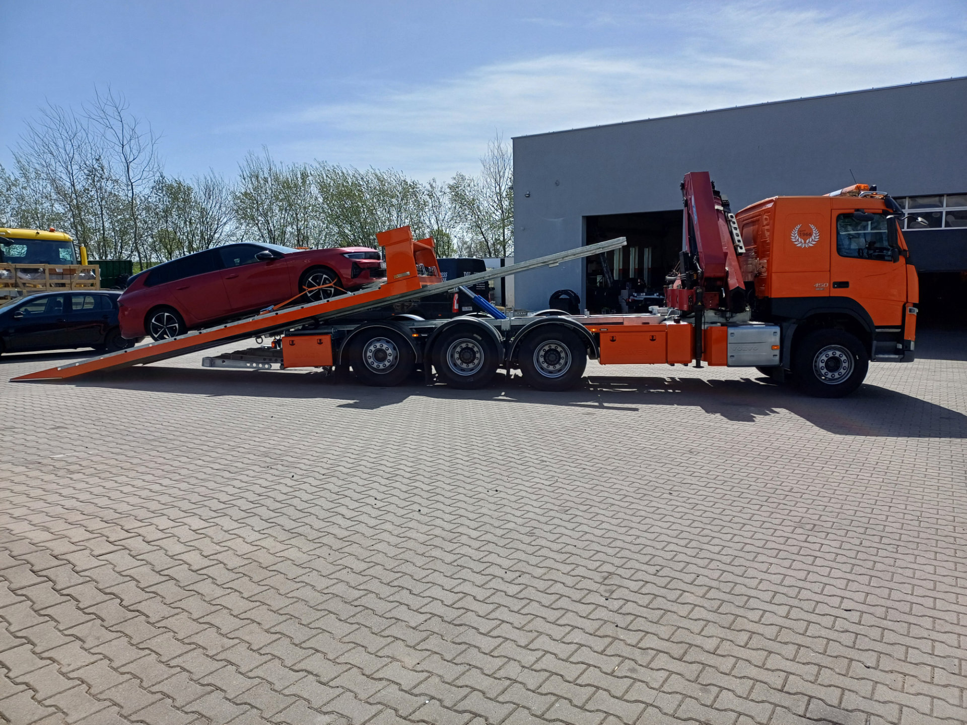 Ciężarówka Volvo FM 450 z platformą hydrauliczną i samochodem.