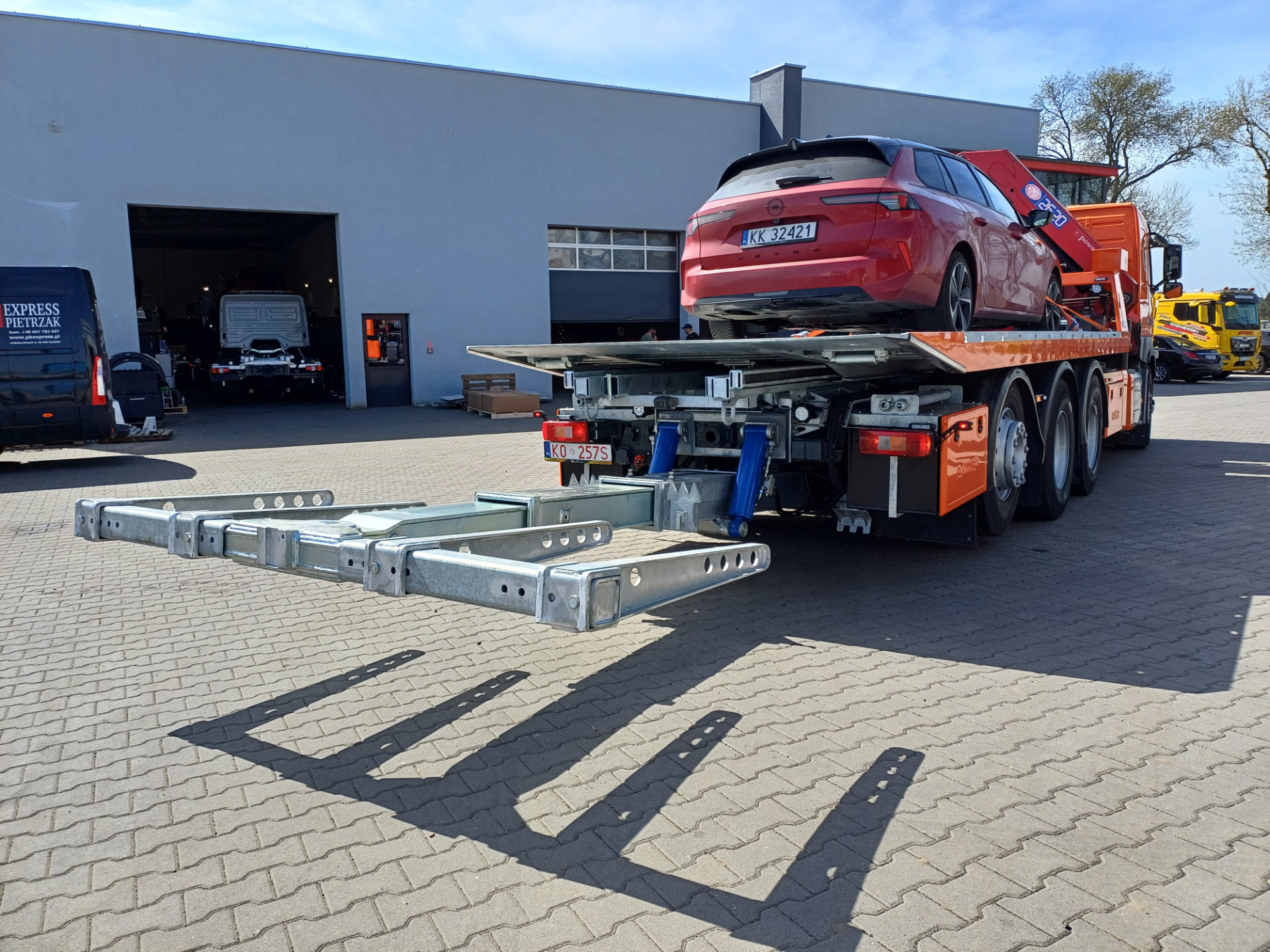 laweta volvo fm 450 z czerwoną osobówką na platformie hydraulicznej