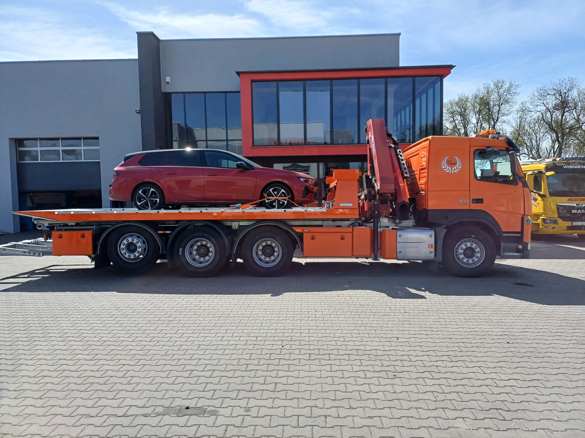 pomarańczowa laweta volvo fm 450 z samochodem osobowym