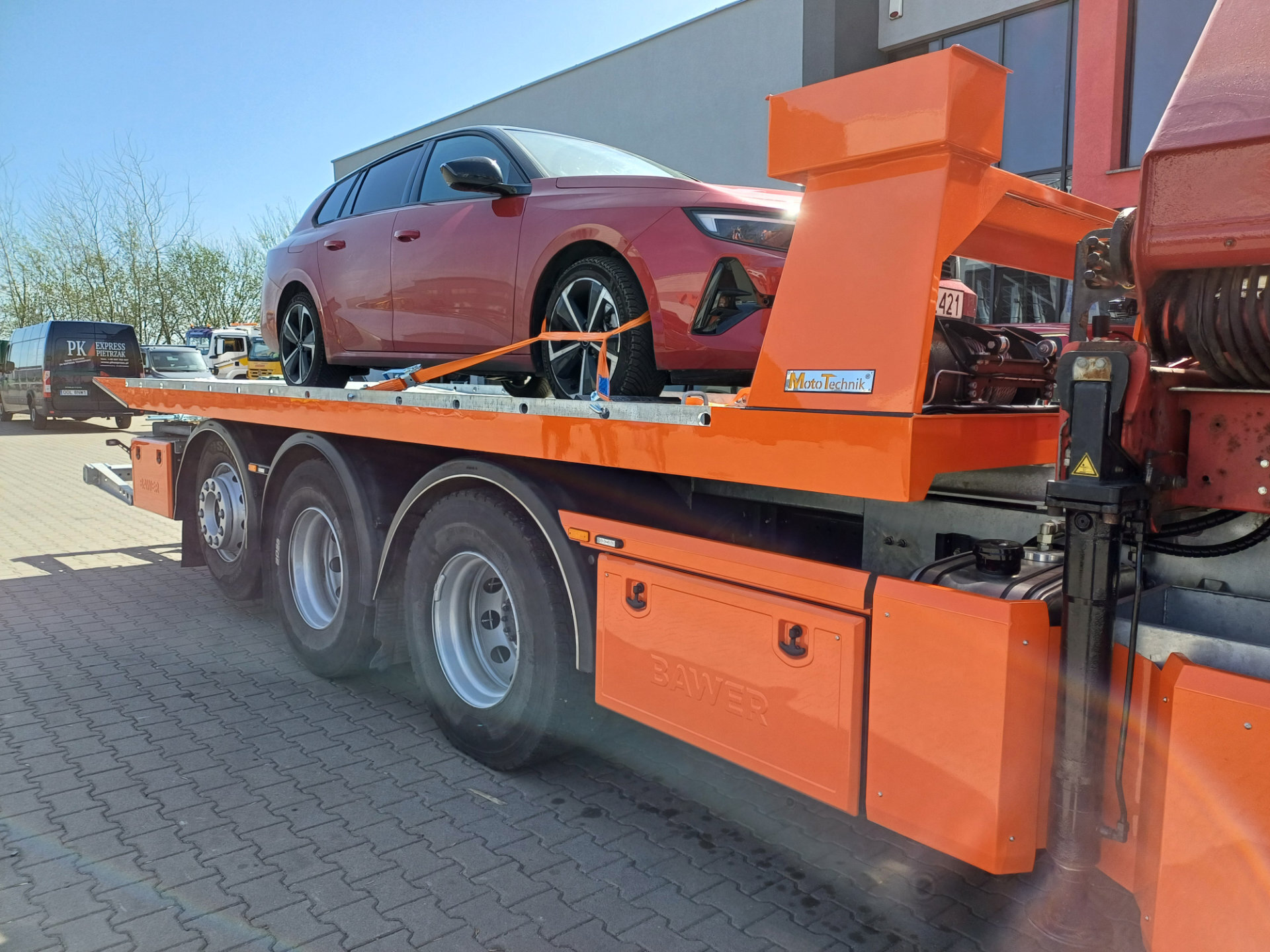 Czerwony samochód na pomarańczowej platformie hydraulicznej Volvo FM 450