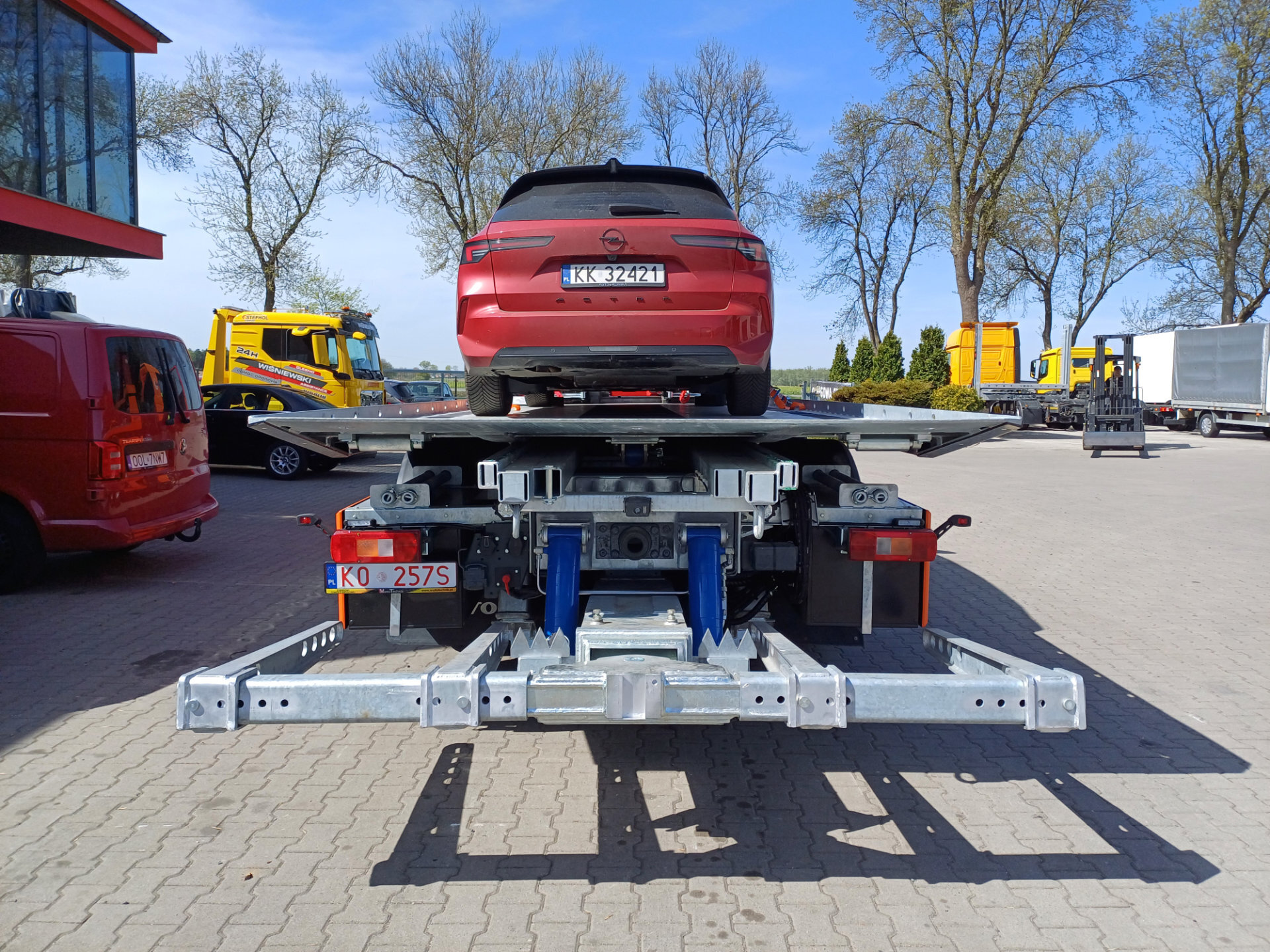 czerwona osobowa na platformie hydraulicznej samochód transportowy Volvo